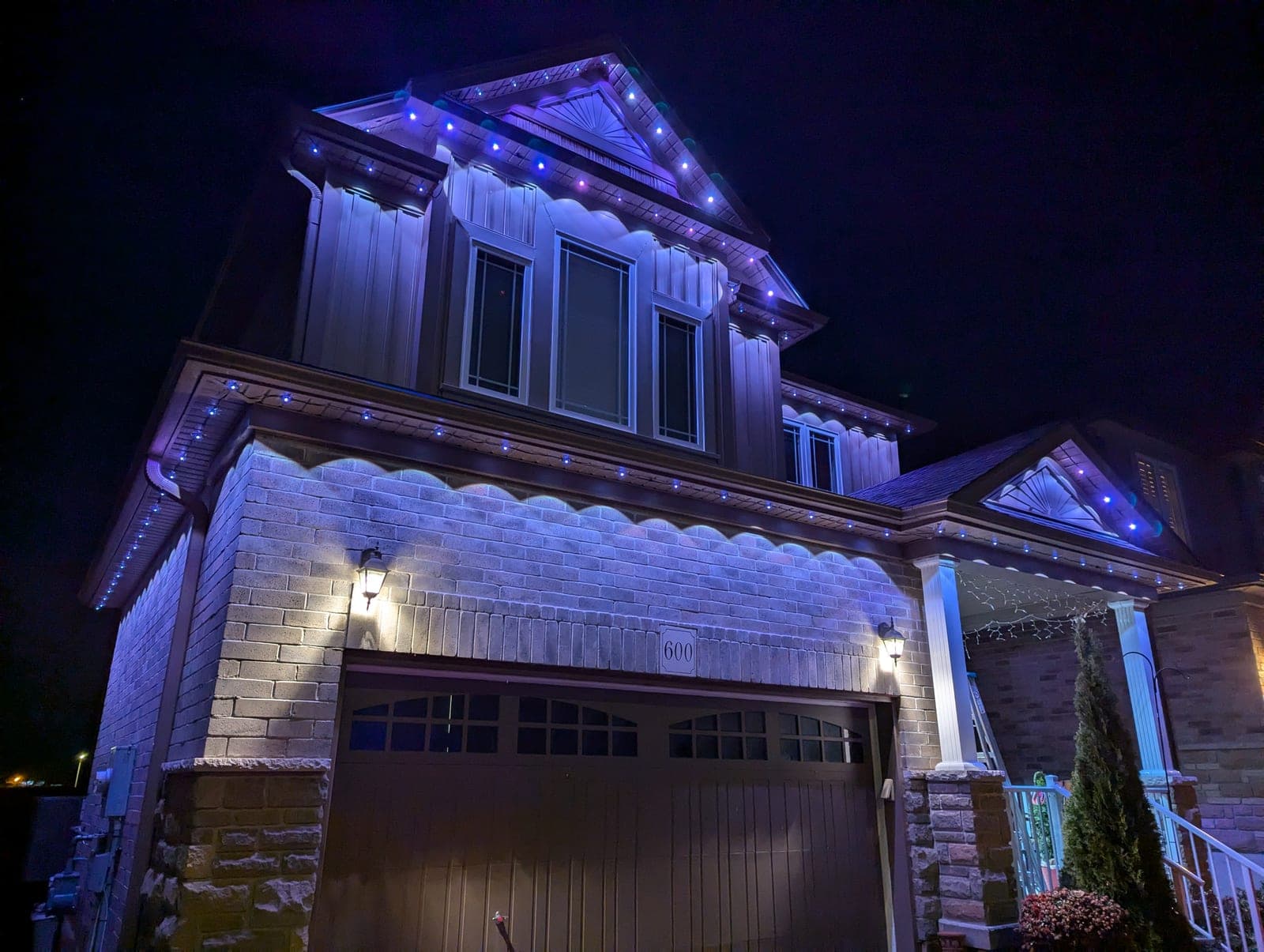 Front view of a two-storey home lit in blue with permanent LED holiday lighting